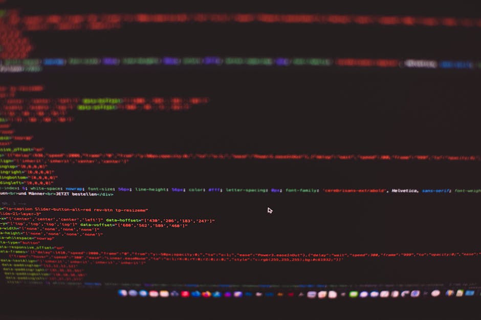 A pair of hands typing on a laptop keyboard, which displays lines of code on a dark screen with various syntax highlighting in green, blue, and white. The laptop is positioned on a smooth, reflective 